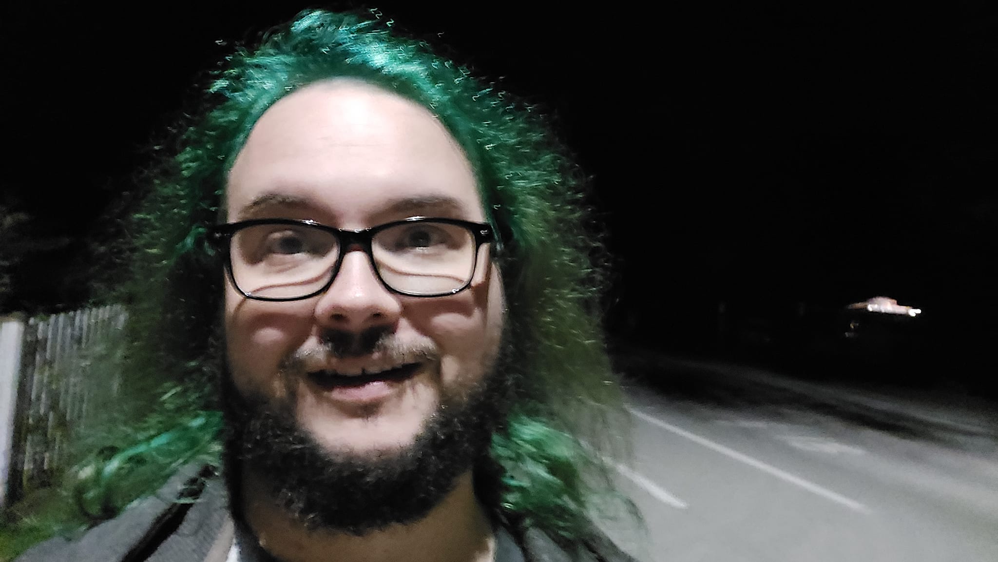 A man with green hair is outside after dark, Photo 13